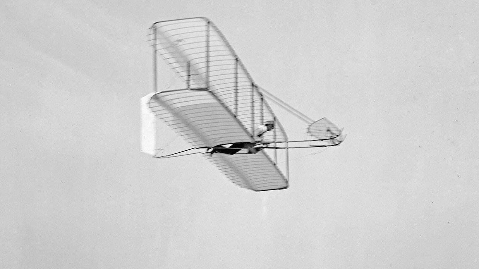 ภาพขาวดำปี 1902 วิลเบอร์ ไรท์ร่อนเครื่องร่อนปีกสองชั้นเหนือเนินทรายที่ Kitty Hawk